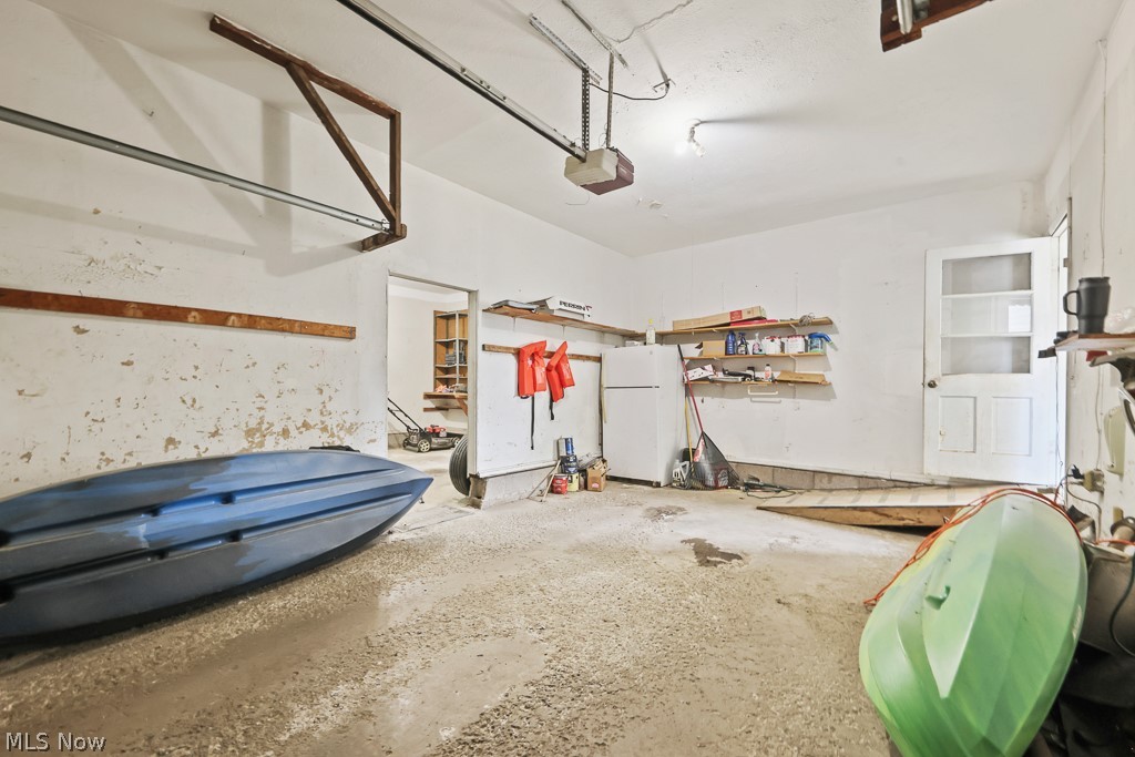 611 Herbert Road Akron, OH 44312 - Photo 28 of 30 Garage space featuring a concrete floor, overhead garage door track system, exposed ceiling joists, and a side access door with glass panels