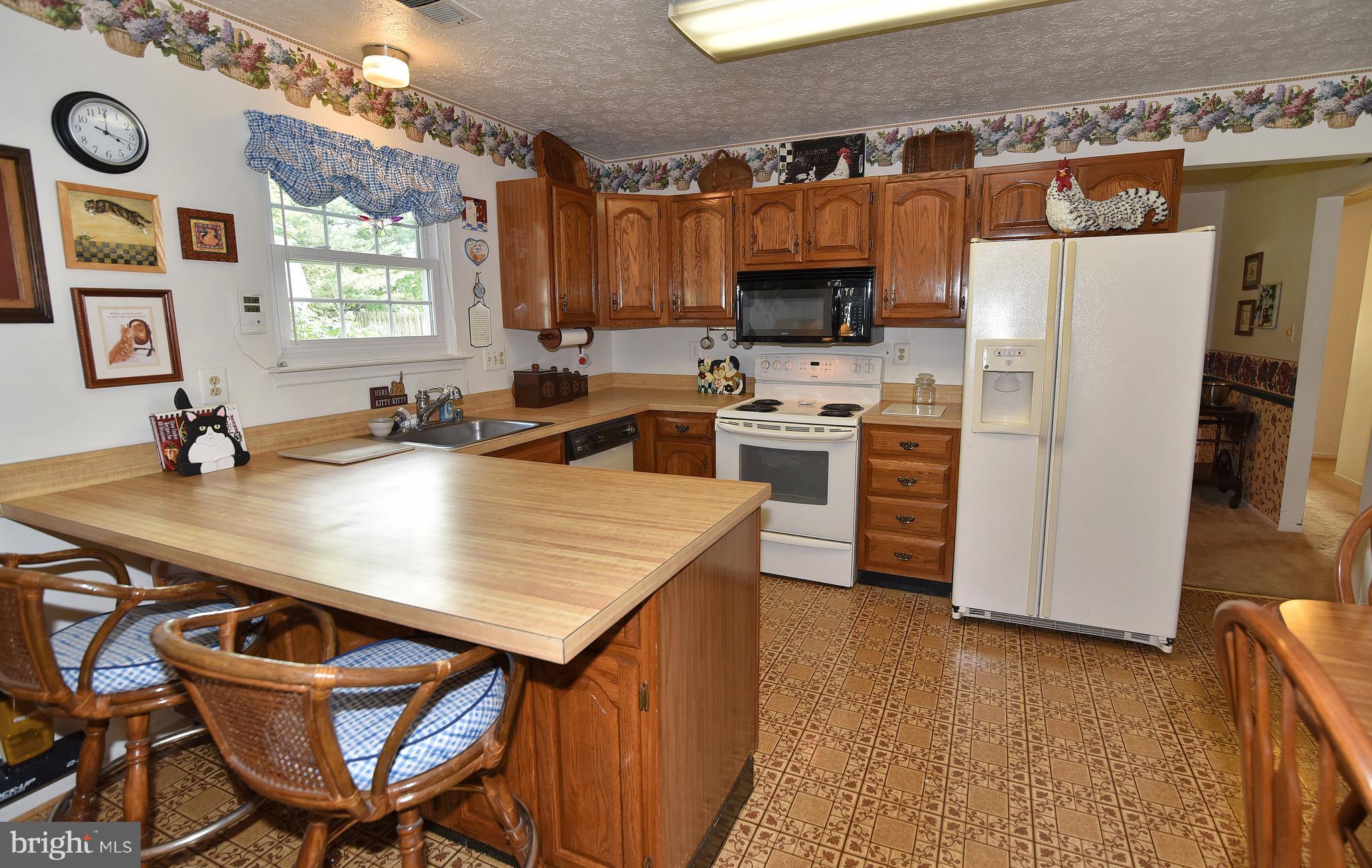 8219 Grainfield Road Severn, MD 21144 - Photo 11 of 30 a kitchen with stainless steel appliances a table chairs and a refrigerator