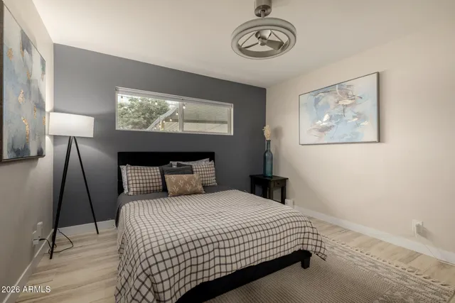 a bedroom with a bed and a lamp on table with wooden floor