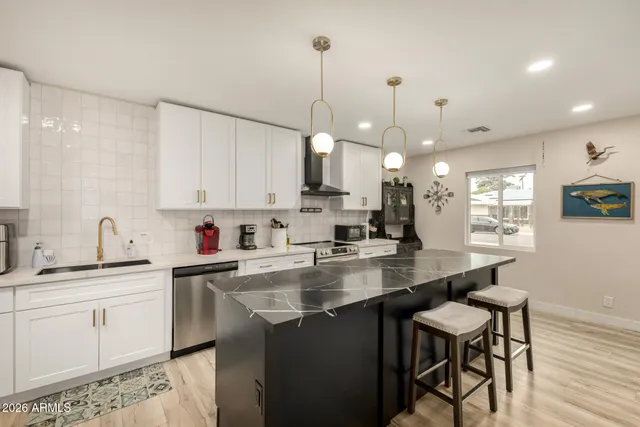 a kitchen with kitchen island granite countertop a sink a center island a counter space and cabinets
