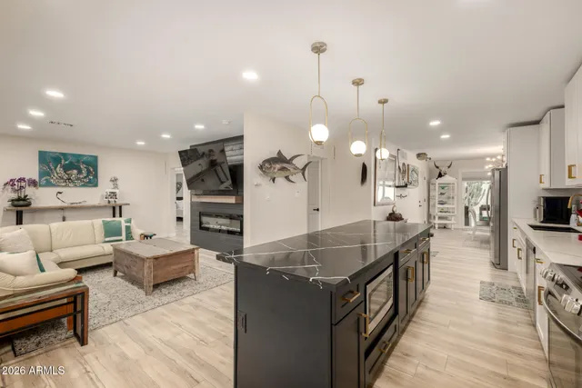 a large kitchen with kitchen island a large counter top stainless steel appliances and a chandelier
