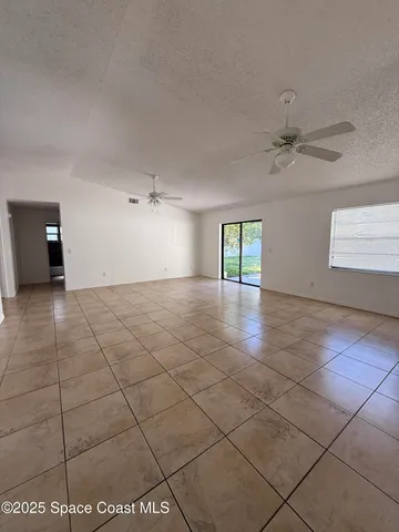 an empty room with windows and ceiling fan