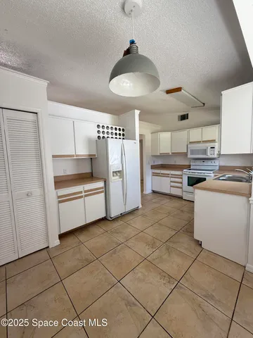 a kitchen with granite countertop a refrigerator and a stove top oven