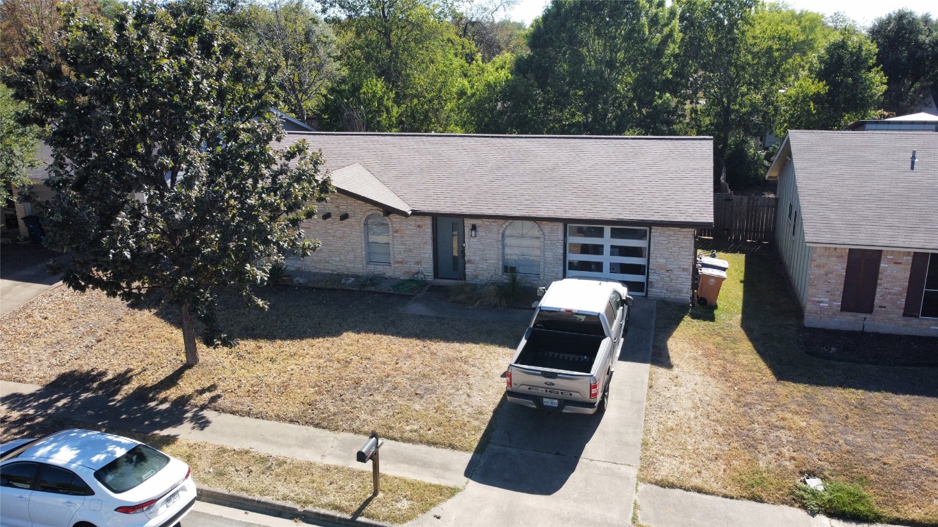 View of front of home with a shingled roof, brick siding, concrete driveway, and a garage