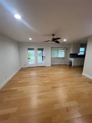 a view of an empty room with window and wooden floor