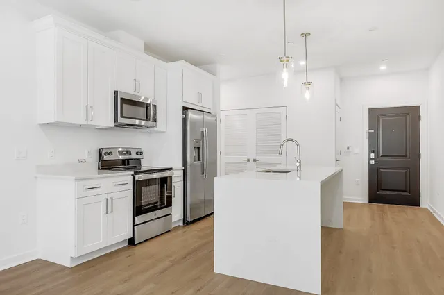 a kitchen with stainless steel appliances a refrigerator sink and white cabinets