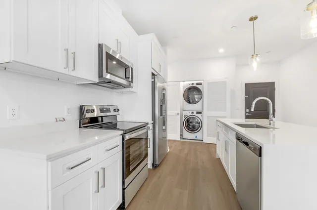 a kitchen with stainless steel appliances granite countertop a stove a sink dishwasher and a refrigerator with wooden cabinets