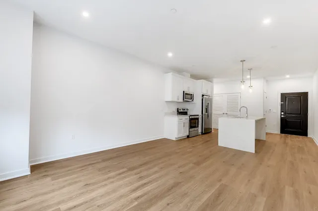 a view of a kitchen with refrigerator and wooden floor