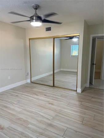 en empty room with wooden floor chandelier and windows