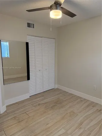 an empty room with wooden floor chandelier fan and windows