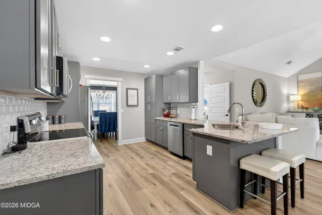 a kitchen with stainless steel appliances granite countertop a refrigerator a sink dishwasher and wooden cabinets with wooden floor