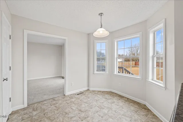 an empty room with chandelier fan and windows