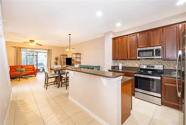 a kitchen with stainless steel appliances granite countertop a stove top oven a sink dishwasher a dining table and chairs with wooden floor