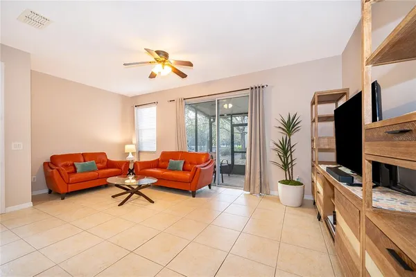 a living room with furniture a flat screen tv and floor to ceiling window