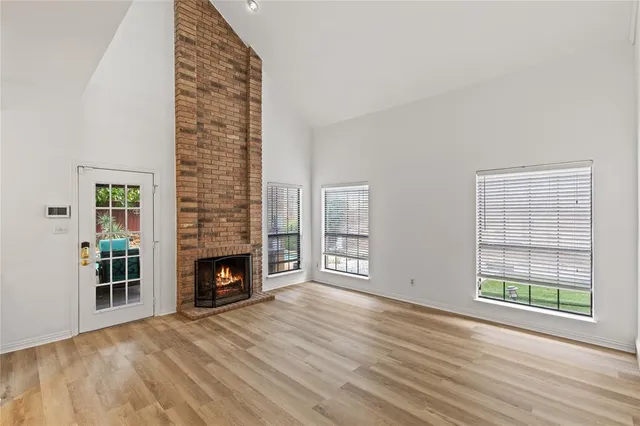 an empty room with windows fire place and refrigerator