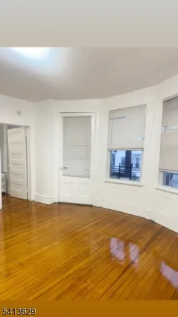 a view of an empty room with window and wooden floor