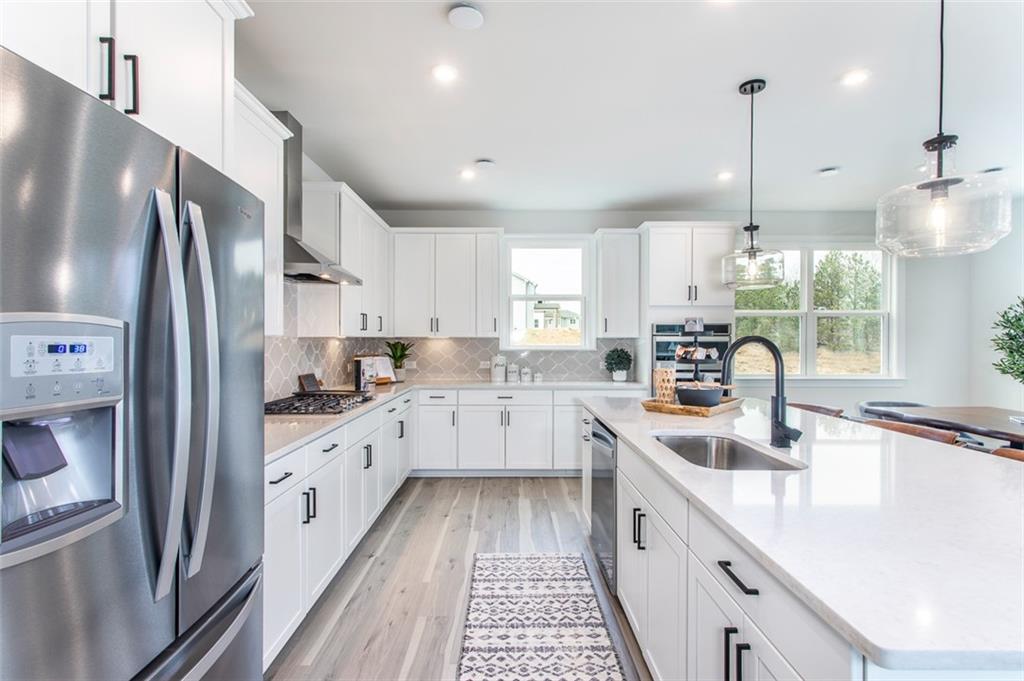 4840 Montane Street Cumming, GA 30028 - Photo 17 of 34 a kitchen with white cabinets and stainless steel appliances