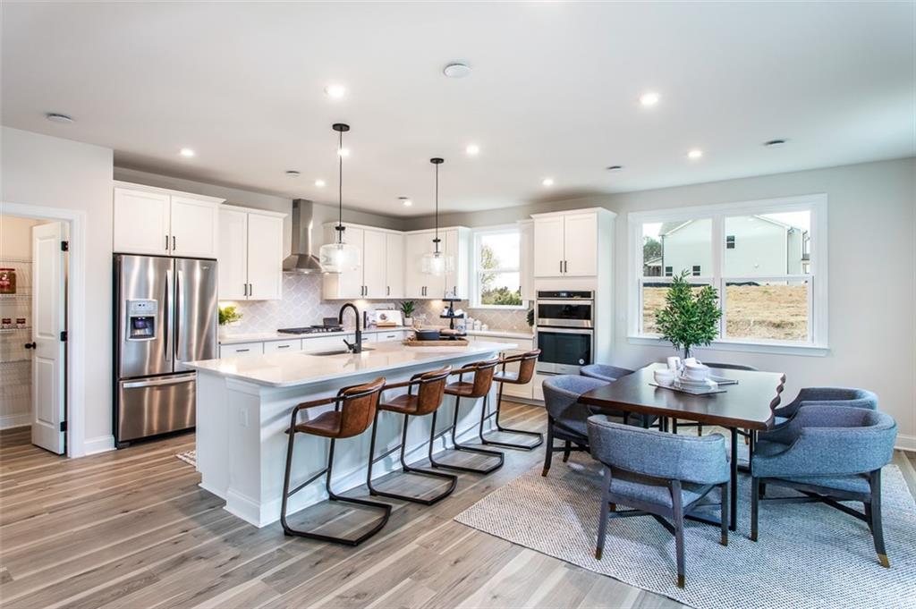 4840 Montane Street Cumming, GA 30028 - Photo 18 of 34 a kitchen with stainless steel appliances granite countertop a table chairs refrigerator and a sink