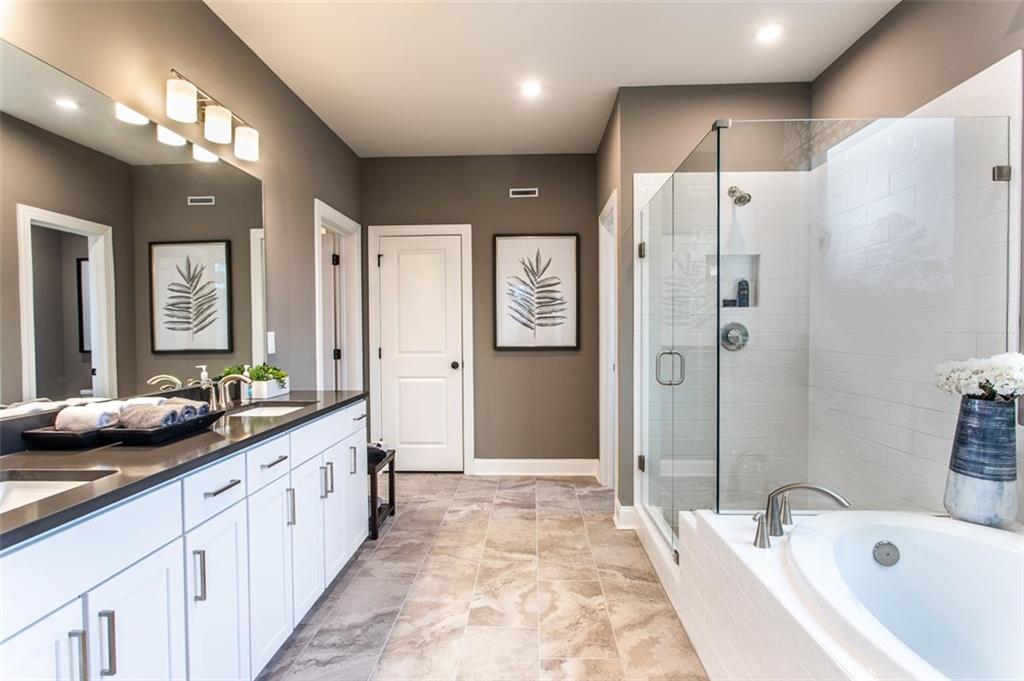 4840 Montane Street Cumming, GA 30028 - Photo 21 of 34 a bathroom with double vanity sinks a shower and a bathtub