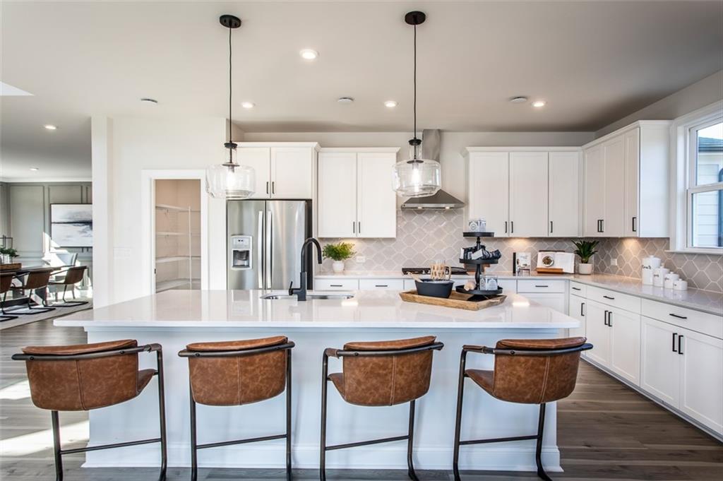 4840 Montane Street Cumming, GA 30028 - Photo 26 of 34 a kitchen with stainless steel appliances granite countertop a kitchen island a stove a cabinets and chairs