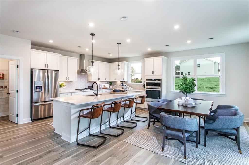 4840 Montane Street Cumming, GA 30028 - Photo 4 of 34 a kitchen with stainless steel appliances granite countertop a stove a refrigerator a kitchen island a dining table and chairs