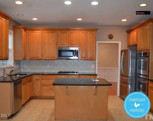 a kitchen with stainless steel appliances granite countertop a refrigerator a sink a stove a microwave a counter space and cabinets