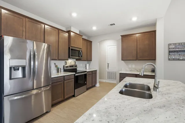 a kitchen with granite countertop a sink stainless steel appliances and cabinets