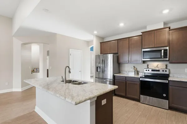 a kitchen with kitchen island granite countertop a sink stove refrigerator and cabinets