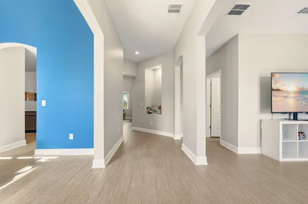 a view of a hallway with wooden floor and a bathroom