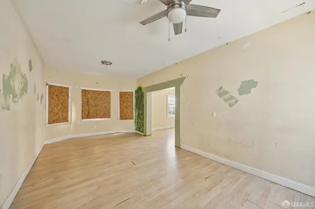 an empty room with wooden floor fan and windows