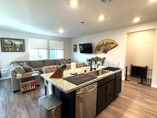 a living room with stainless steel appliances granite countertop couches a fireplace a flat screen tv and kitchen view