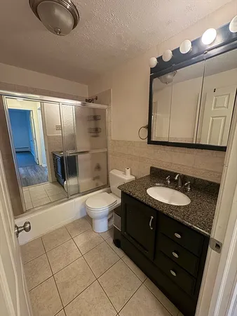 a bathroom with a granite countertop sink toilet and mirror