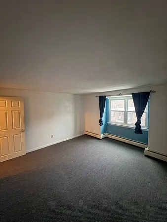an empty room with a window and fireplace