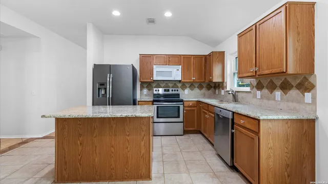 a kitchen with stainless steel appliances granite countertop a stove top oven a sink and a refrigerator