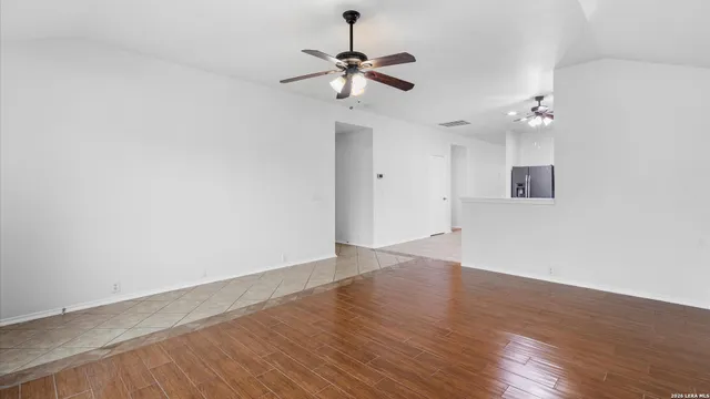 a view of a room with wooden floor and a ceiling fan