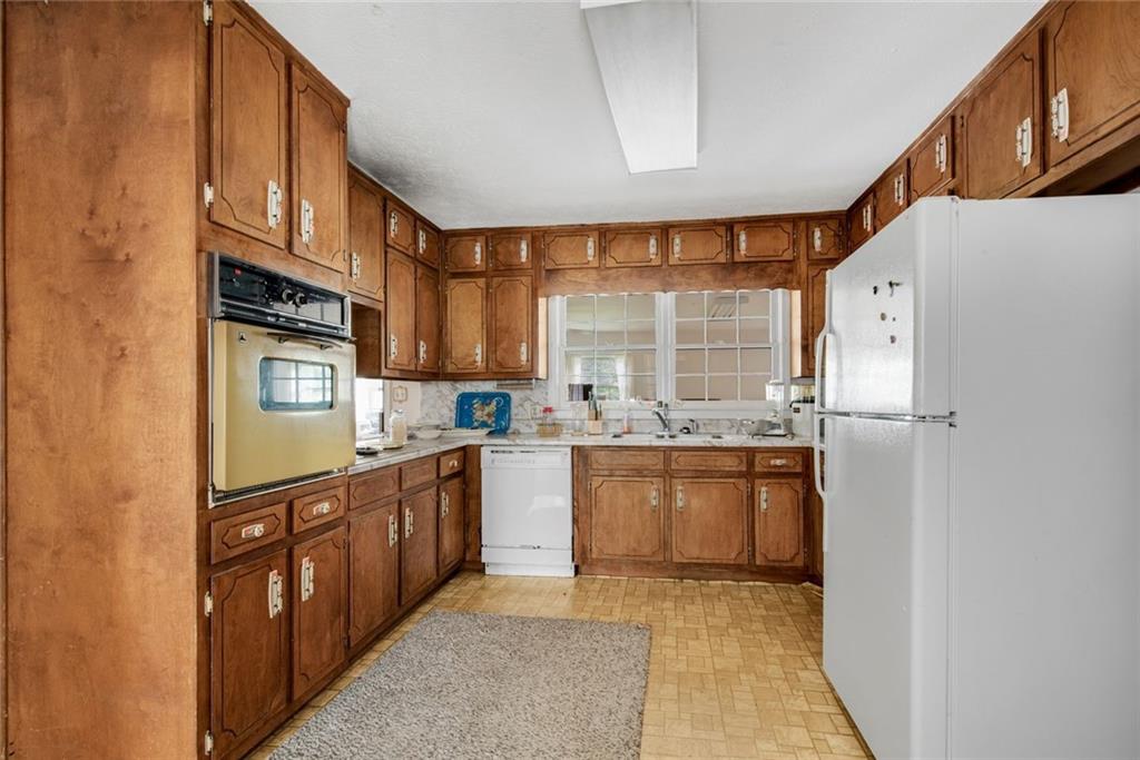 1955 Flat Shoals Road Southeast Conyers, GA 30013 - Photo 17 of 56 a kitchen with stainless steel appliances granite countertop a refrigerator a sink dishwasher a stove with wooden cabinets and floor