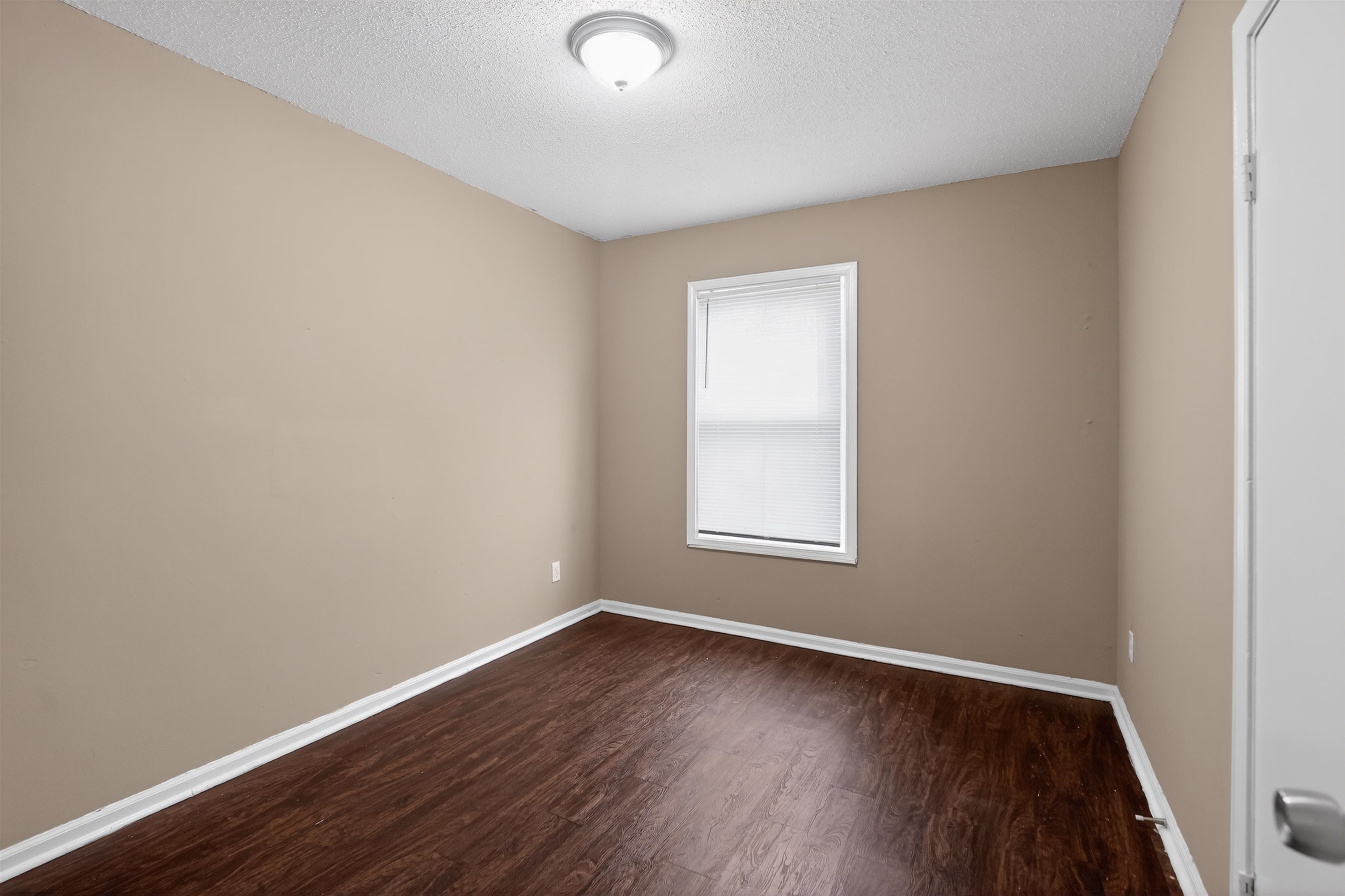 3608 Cane Ridge Drive Memphis, TN 38109 - Photo 15 of 31 Room featuring wood-finish flooring, neutral wall paint, white trim, a single window, and a flush-mount ceiling light fixture