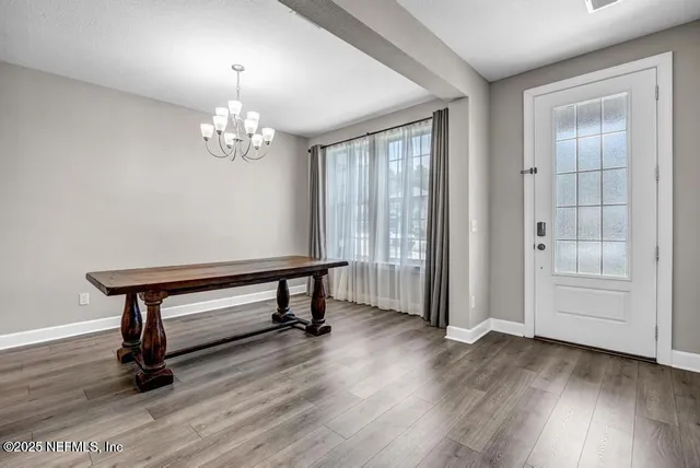 a view of a room with wooden floor a chandelier and windows
