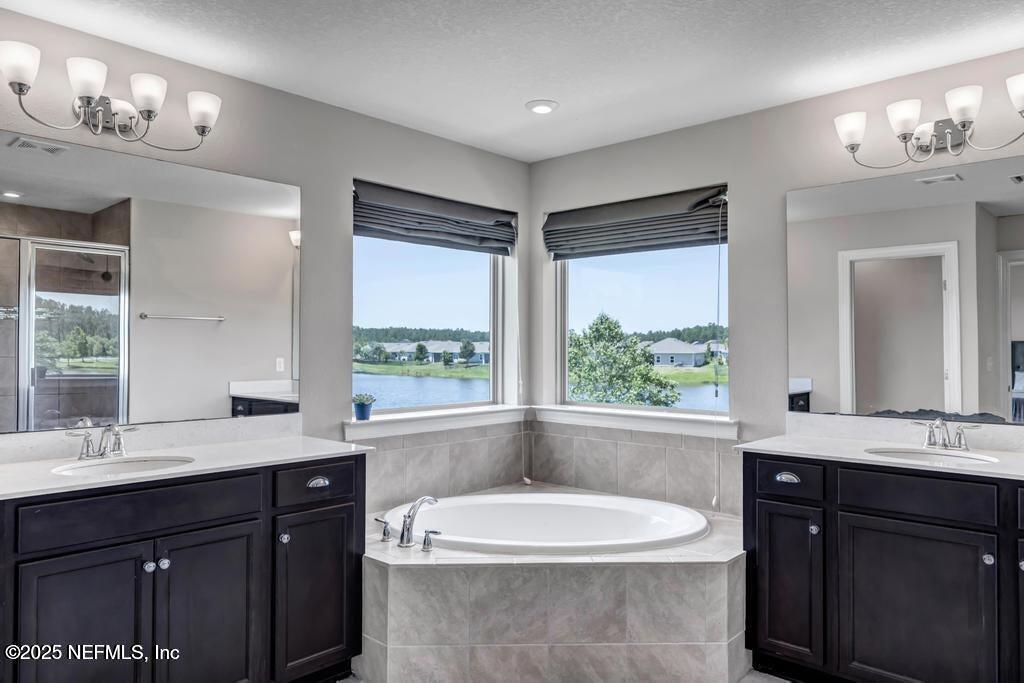 23 Catesby Lane St. Augustine, FL 32095 - Photo 20 of 31 a bathroom with a double vanity sink a large mirror a bathtub and window
