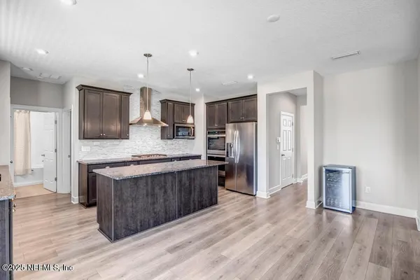 a large kitchen with stainless steel appliances granite countertop a stove a sink dishwasher a refrigerator and a oven with wooden floor