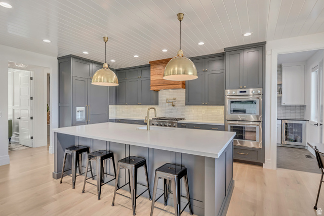 1720 Hillcrest Circle Mapleton, UT 84664 - Photo 45 of 116 Kitchen with gray cabinets, a breakfast bar area, stainless steel appliances, a large island, and decorative light fixtures