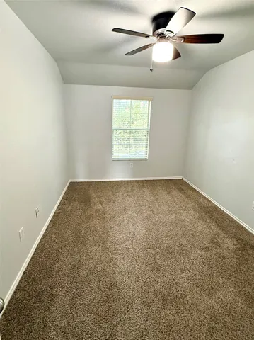 an empty room with a window and a ceiling fan