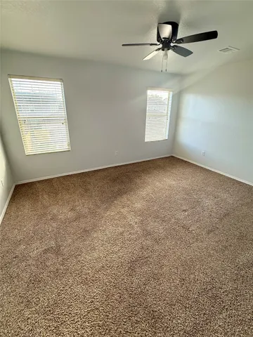 an empty room with windows and fan