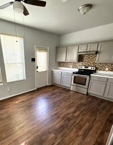a kitchen with a stove wooden floor and white cabinets