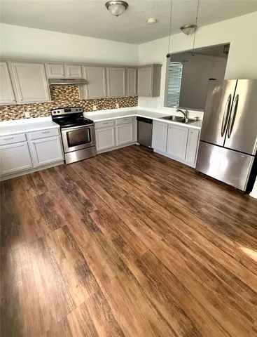 a large kitchen with a wooden floor and stainless steel appliances