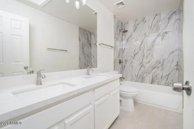 a bathroom with a granite countertop sink mirror vanity and toilet