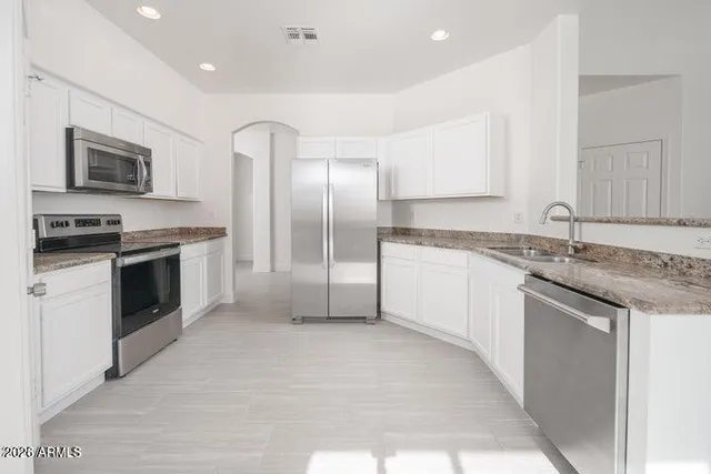 a kitchen with stainless steel appliances granite countertop a stove a sink and a refrigerator