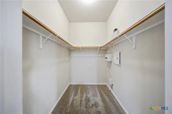 an empty room with kitchen and chandelier fan