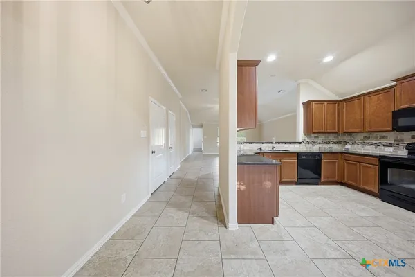 a large kitchen with granite countertop a stove a sink a counter space and cabinets