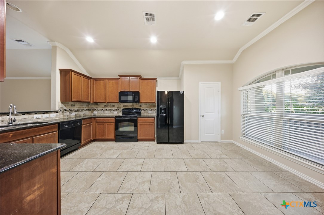 728 Olaf Drive Temple, TX 76504 - Photo 6 of 26 a large kitchen with granite countertop a stove a sink a counter space and cabinets